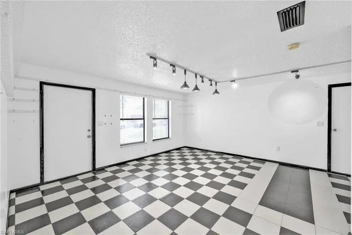 Empty room featuring track lighting, a textured ceiling, a smoke detector, and tile patterned floors