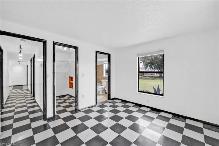 Unfurnished bedroom with a textured ceiling, dark flooring, and ensuite bathroom