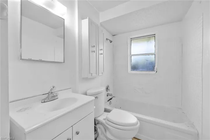 Full bath featuring toilet, vanity, shower / bath combination, and a textured ceiling
