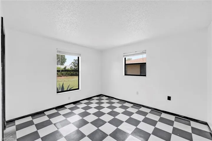 Unfurnished room featuring tile patterned floors, a textured ceiling, and baseboards