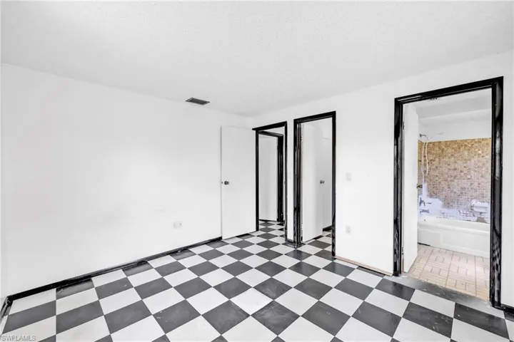 Unfurnished bedroom with tile patterned floors, a textured ceiling, and ensuite bathroom
