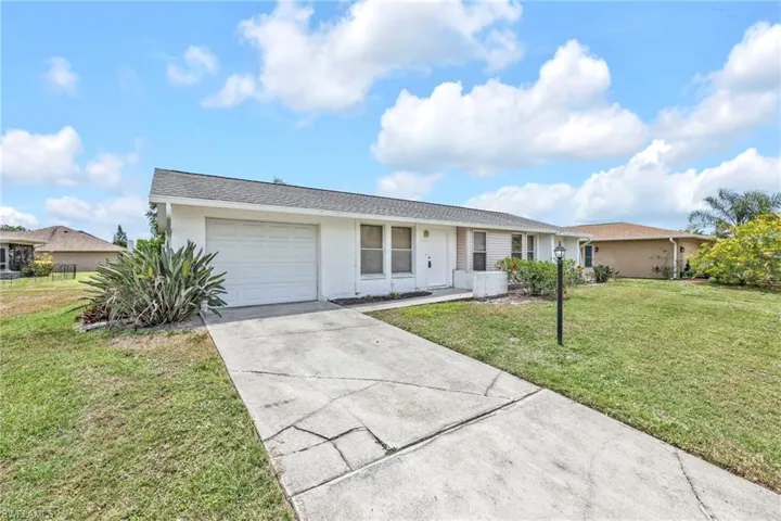 Single story home with a garage, concrete driveway, a front lawn, and stucco siding