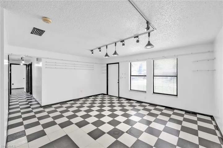 Empty room featuring light flooring, a textured ceiling, and rail lighting