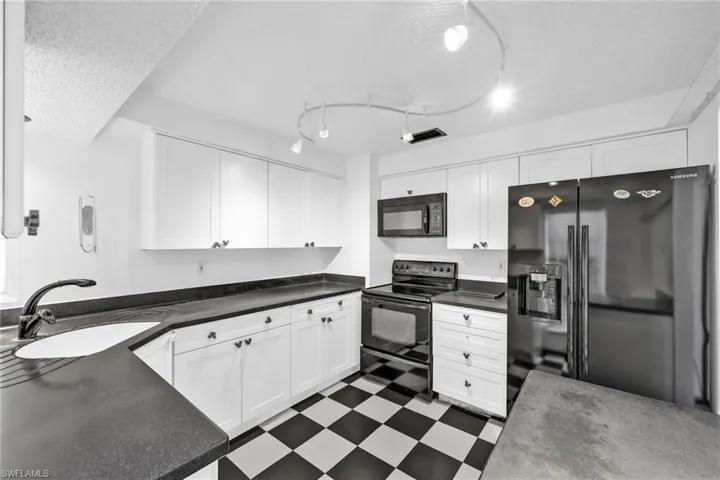 Kitchen with black appliances, a sink, dark floors, a textured ceiling, and white cabinetry