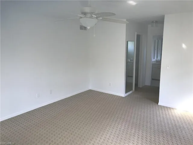 Carpeted empty room featuring a ceiling fan and baseboards