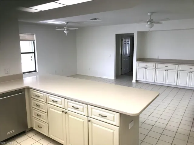 Kitchen with ceiling fan, a peninsula, light tile patterned flooring, and stainless steel dishwasher