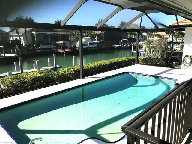 Swimming pool with a sunroom, a water view, a dock, and glass enclosure