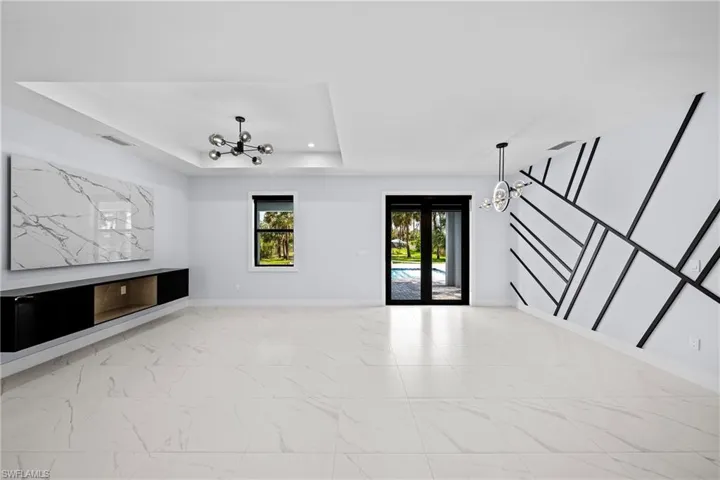 Unfurnished living room featuring marble finish flooring, baseboards, a tray ceiling, and recessed lighting
