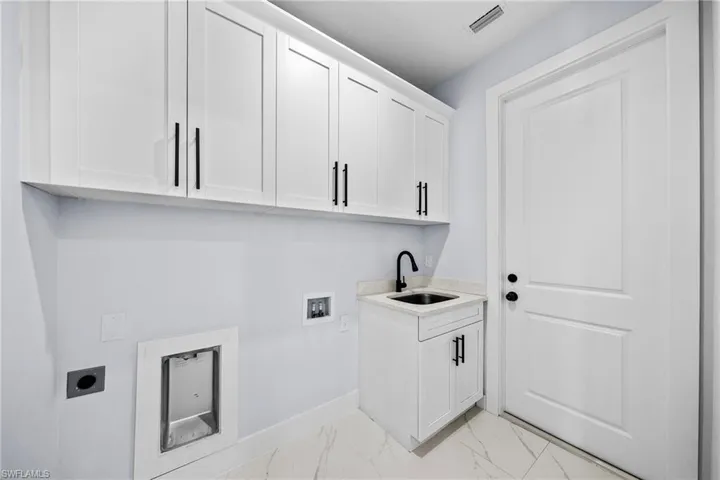 Laundry area with hookup for an electric dryer, cabinet space, baseboards, light marble finish floors, and hookup for a washing machine