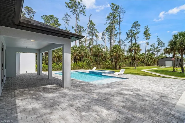 View of pool with a patio, a yard, and a pool with connected hot tub