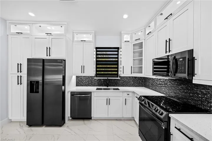 Kitchen featuring slate Samsung fingerless appliances, a sink, light marble finish flooring, white cabinets, and recessed lighting