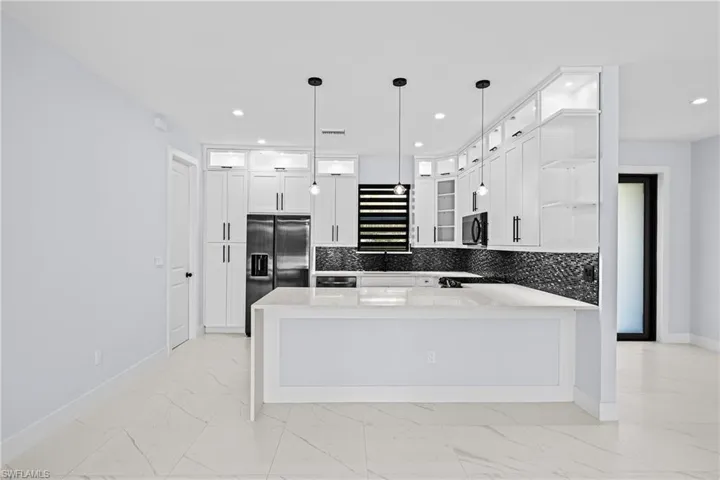 Kitchen featuring slate Samsung fingerless appliances, open shelves, light marble finish flooring, a peninsula, and recessed lighting