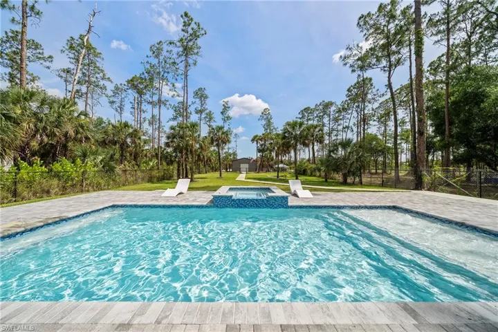 View of heated swimming pool featuring a pool with connected hot tub