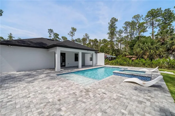 View of pool with a patio and a pool with connected hot tub