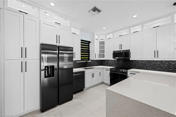 Kitchen with stainless steel slate fridge with ice dispenser, dishwashing machine, electric stove, light marble finish floors, and light stone counters