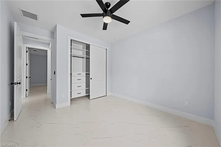 Unfurnished bedroom featuring light marble finish floors and baseboards