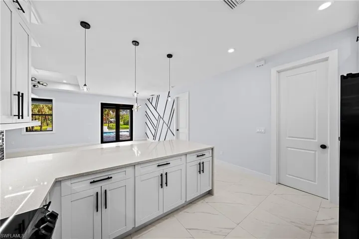 Kitchen featuring white quartz counters, recessed lighting, white cabinetry, pendant lighting, and light marble finish floors