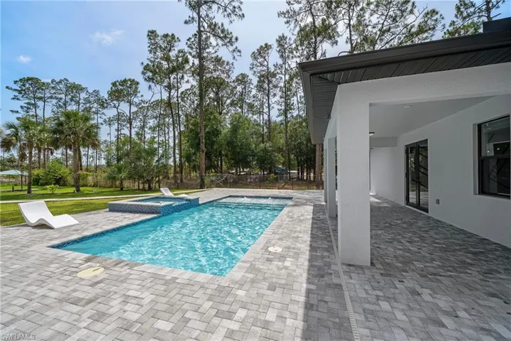 View of pool with a patio and a pool with connected hot tub