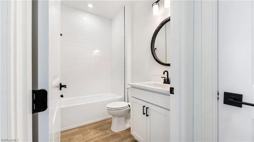 Bathroom with vanity, wood finish floors, and  shower combination