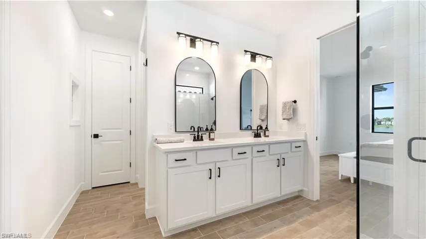 Bathroom featuring double vanity, wood tiled floors, and a shower stall