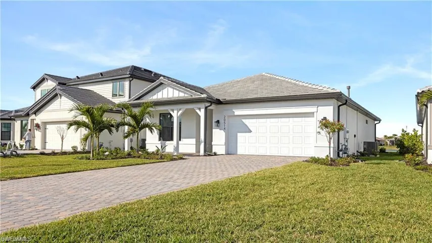 View of front of house with a front yard, decorative driveway, a garage, stucco siding, and a porch