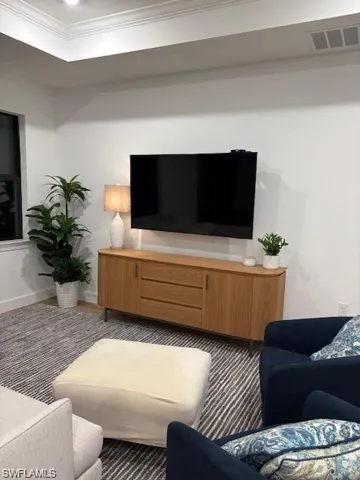 Living area featuring a raised ceiling and ornamental molding