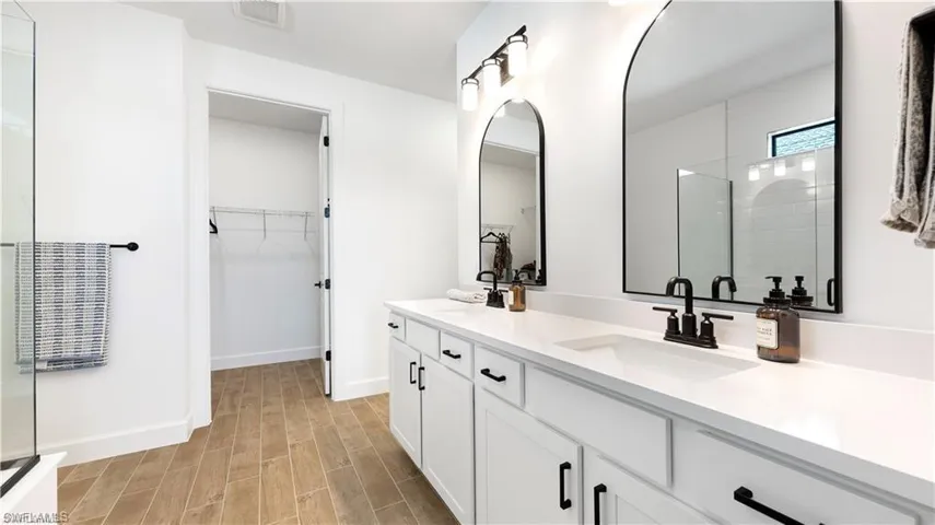 Full bathroom with a stall shower, double vanity, wood tiled floors, and a spacious closet