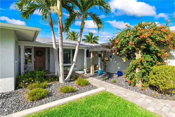 Front entrance featuring a meticulously designed paver driveway with tropical accents.