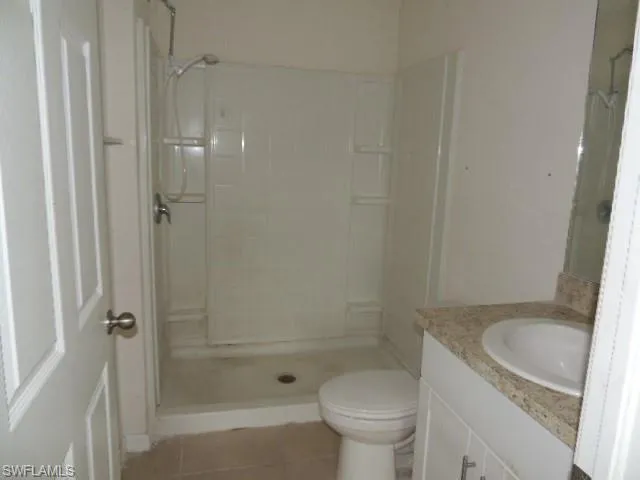 Bathroom featuring vanity, light tile patterned floors, and a stall shower