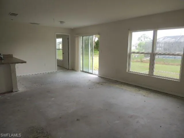 Empty room with healthy amount of natural light and unfinished concrete floors