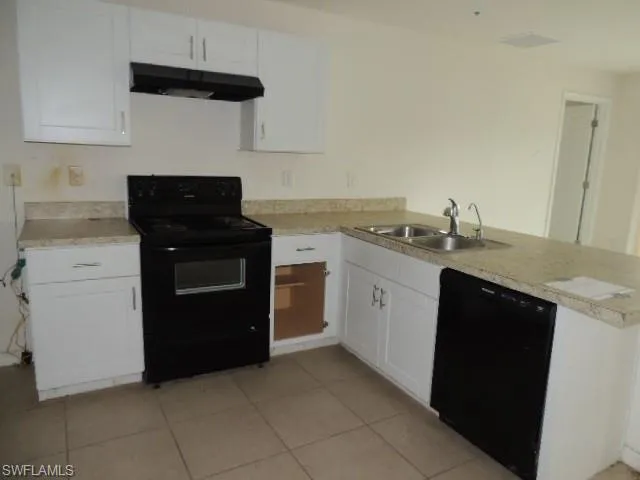 Kitchen with black appliances, white cabinetry, and light countertops