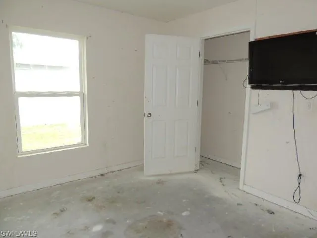 Unfurnished bedroom with concrete flooring and a closet