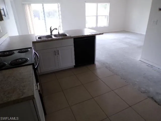 Kitchen featuring range with electric stovetop, white cabinets, black dishwasher, light countertops, and light tile patterned floors