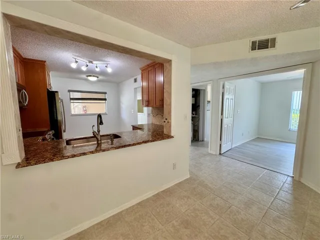 Kitchen pass-through featuring a granite countertop with an undermount sink and gooseneck faucet
