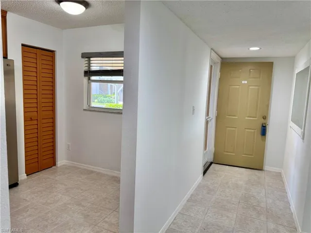 Tiled entryway featuring a panel door, recessed lighting, and a louvered bi-fold closet door