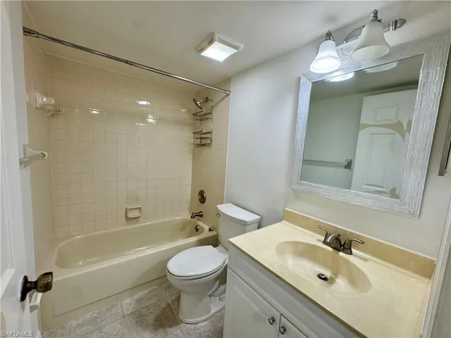 Bathroom with a white vanity cabinet, a light-colored countertop with an integrated sink, and a rectangular mirror featuring a textured frame