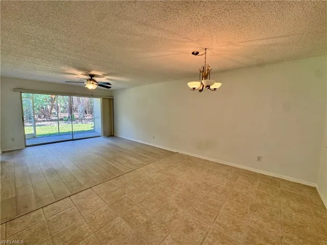 Interior living space featuring sliding glass doors to outdoor area, tile flooring, wood-look flooring, ceiling fan, and overhead chandelier