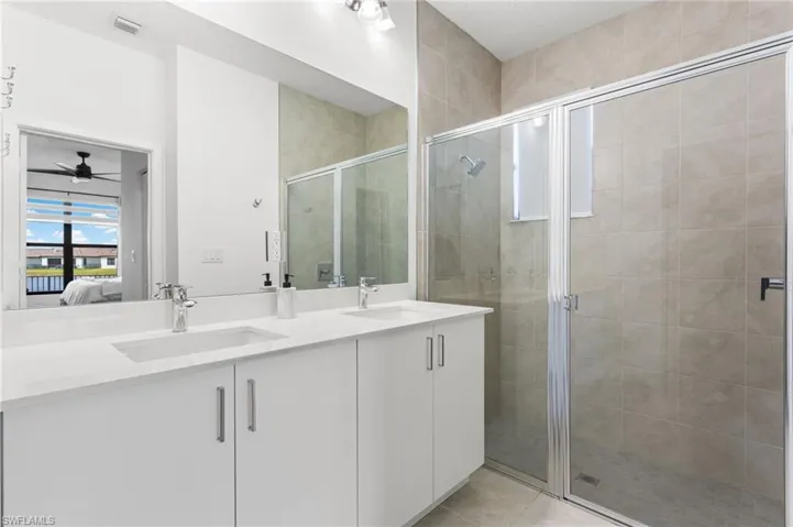 Ensuite bathroom with double vanity, a stall shower, and light tile patterned flooring