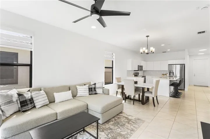 Living room with a ceiling fan, suspended lighting, and light tile patterned floors