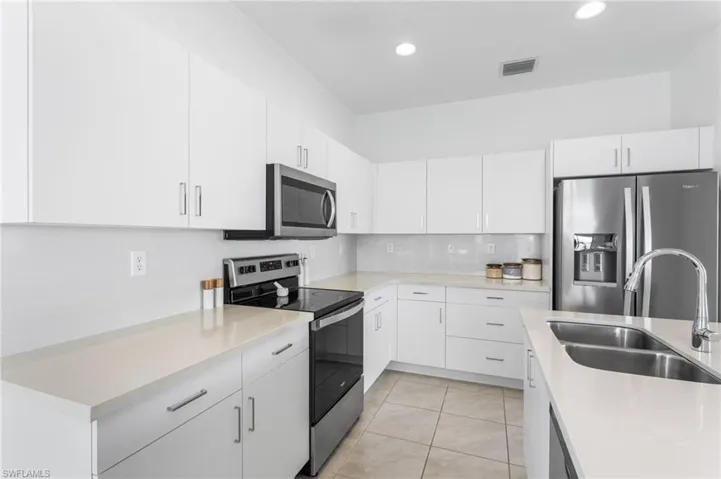 Kitchen featuring stainless steel appliances, white cabinetry, light tile patterned flooring, tasteful backsplash, and recessed lighting