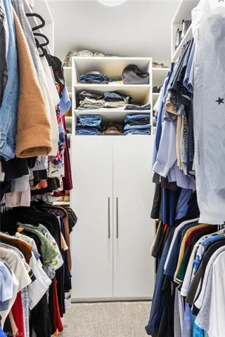 Walk in closet featuring light colored carpet