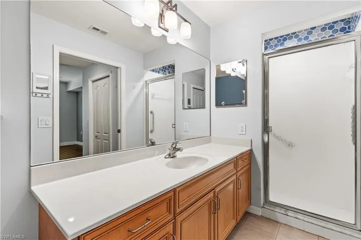 Bathroom featuring tile patterned flooring, walk in shower, and vanity