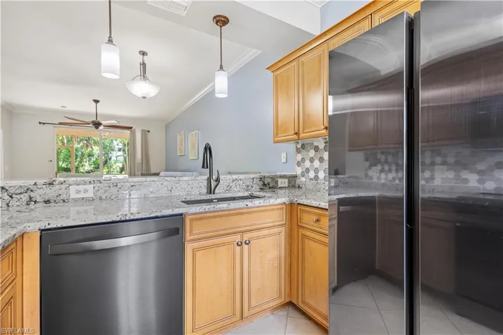 Kitchen featuring light tile patterned flooring, stainless steel dishwasher, ceiling fan, and hanging light fixtures