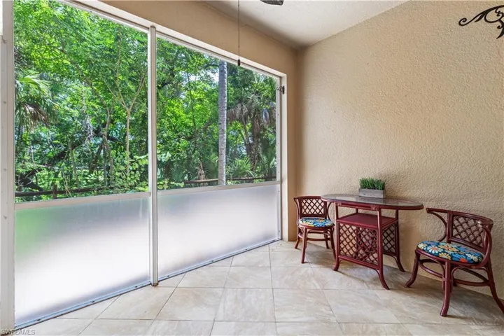 Private screened-in lanai with lofted ceiling and light tile patterned floors