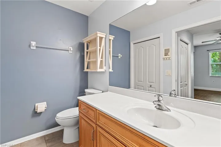 Bathroom featuring tile patterned floors, vanity, ceiling fan, and toilet