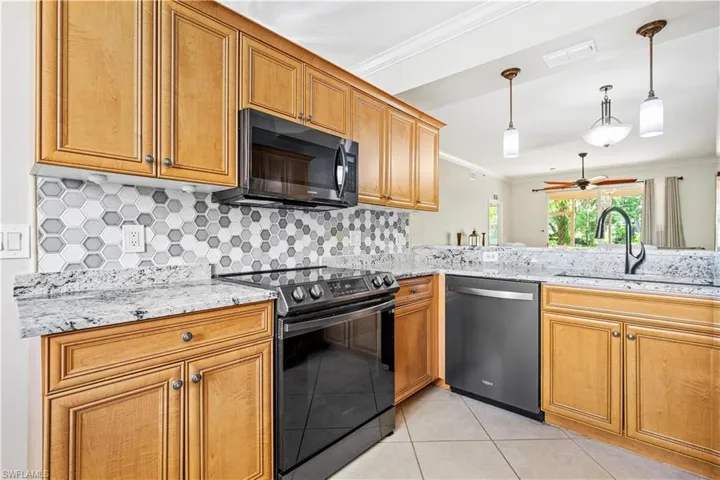 Kitchen with tasteful backsplash, stainless steel appliances, sink, hanging light fixtures, and ceiling fan