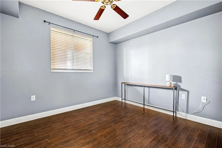Empty room with dark hardwood / wood-style floors and ceiling fan