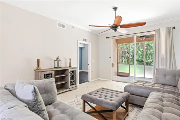 Tiled living room with crown molding and ceiling fan