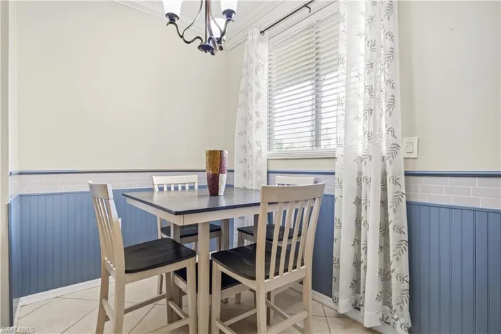 Dining space with ornamental molding, an inviting chandelier, and light tile patterned floors