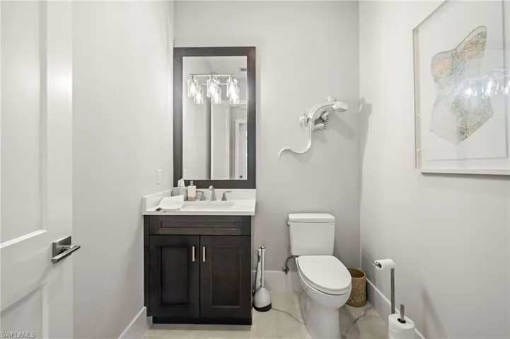 Powder room featuring a dark wood-finish vanity with a white countertop, chrome faucet, and a wall-mounted light fixture